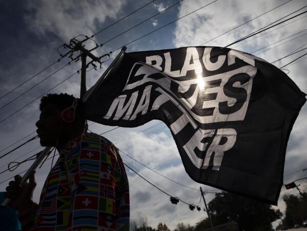 FILE - In this Dec. 12, 2020, file photo, MD Crawford carries a Black Lives Matter flag before a march in La Marque, Texas to protest the shooting of Joshua Feast, 22, by a La Marque police officer. The Black Lives Matter Global Network Foundation launched a new relief fund Monday, Dec. 12, 2022 aimed at Black college students, alumni and dropouts overburdened by mounting education costs and the student loan debt crisis. (Stuart Villanueva /The Galveston County Daily News via AP, File)