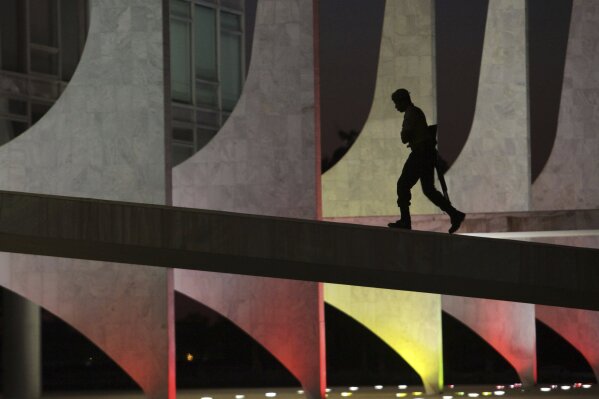 
              A soldier walks up the ramp of the Planalto Presidential Palace, illuminated with the colors of Spain, in honor of the victims of the Barcelona attack, at dawn in Brasilia, Brazil, Friday, Aug. 18, 2017. Spanish police shot and killed five people carrying bomb belts who were connected to the Barcelona van attack that killed at least 13, as the manhunt intensified for the perpetrators of Europe's latest rampage claimed by the Islamic State group. (AP Photo/Eraldo Peres)
            
