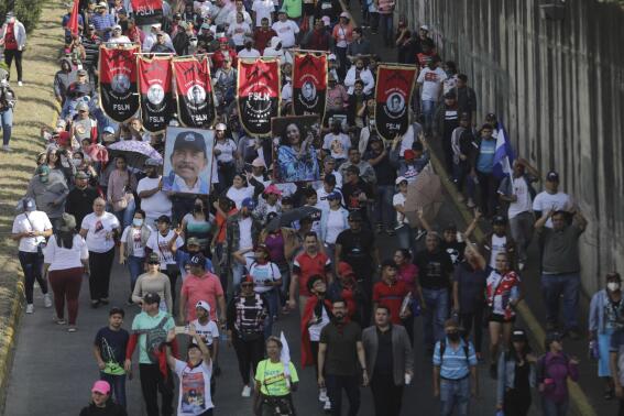 Demonstrators carry Sandinista National Liberation Front banners and a portrait of President Daniel Ortega and Vice President Rosario Murillo, during a pro-government march in Managua, Nicaragua, Saturday, Feb. 11, 2023. (AP Photo)