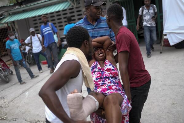 An injured woman is carried to the the Immaculée Conception hospital in Les Cayes, Haiti, Monday, Aug. 16, 2021, two days after a 7.2-magnitude earthquake struck the southwestern part of the country. (AP Photo/Matias Delacroix)