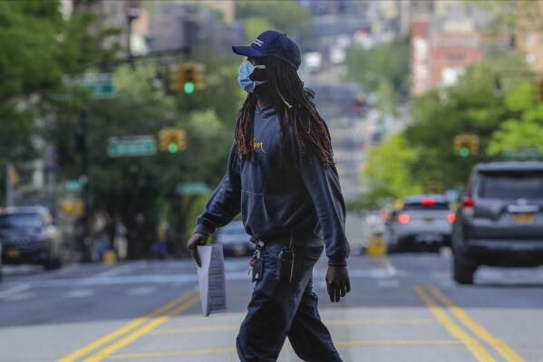 A man wearing a protective mask during the coronavirus pandemic crosses Amsterdam Avenue Wednesday, May 20, 2020, in New York. (AP Photo/Frank Franklin II)