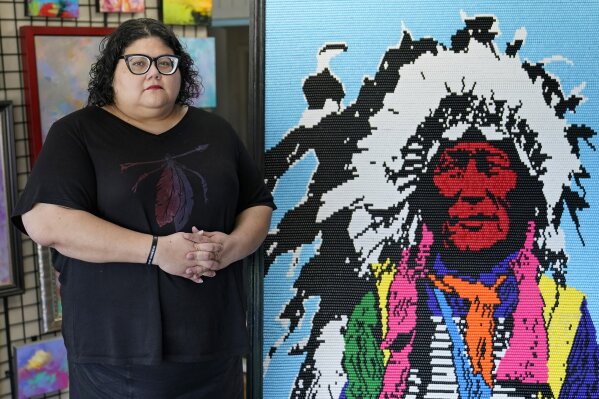 Frances Danger poses for a photo next to a piece of artwork in her family's art gallery, Carpe Artem, Tuesday, Aug. 25, 2020, in Oklahoma City. Danger joined the campaign to pressure Washington's NFL team to drop its offensive name several years ago after her daughter was the target of racist slurs. (AP Photo/Sue Ogrocki)