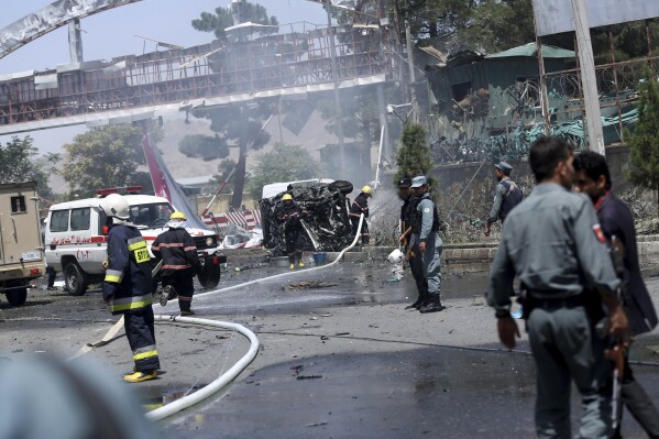 FILE - Afghan fire fighters extinguish vehicles on fire after an attack at the main gate of International Hamed Karzai Airport in Kabul, Afghanistan, Aug. 10, 2015. At a time when Americans are deeply divided along party lines, a new poll shows agreement on at least one issue: the United.States' two-decade long war in Afghanistan was not worth fighting. (AP Photo/Massoud Hossaini, File)