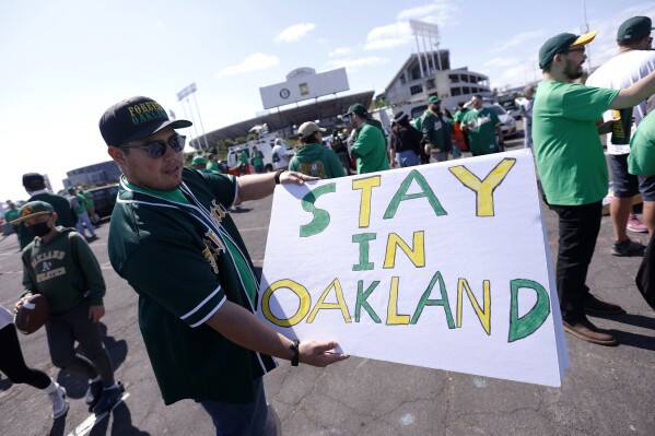 FILE - Reuben Ortiz of Modesto, Calif., holds a sign outside Oakland Coliseum to protest the Oakland Athletics' planned move to Las Vegas, before a baseball game between the Athletics and the Tampa Bay Rays in Oakland, Calif., June 13, 2023. The Athletics’ move to Las Vegas was unanimously approved Thursday, Nov 16, 2023 by Major League Baseball team owners. After years of complaints about the Oakland Coliseum and an inability to gain government assistance for a new ballpark in the Bay area, the A’s plan to move to a stadium to be built on the Las Vegas Strip with $380 million in public financing approved by the Nevada government. (AP Photo/Jed Jacobsohn, file)