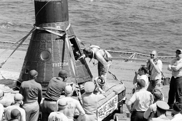 Astronaut Alan B. Shepard Jr., the first American to journey into space, peers into his Freedom 7 space capsule after it is recovered from the Atlantic Ocean and taken aboard the aircraft carrier USS Lake Champlain, May 5, 1961.  The Freedom 7 (MR-7) spacecraft was launched by a Redstone vehicle at 9:34 a.m. EST.  Shepard's flight, return from space, the splashdown at sea and recovery were seen on television by millions of viewers around the world.  (AP Photo)