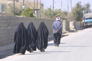 This February 2003 photo provided by photographer Murat Düzyol shows three women walking behind a man in Erbil, Iraq. A version of this original image was manipulated to digitally add chains on the women's ankles, with a caption erroneously claiming it was made in Afghanistan after the Taliban took control of the country in August 2021. (Murat Düzyol via AP)