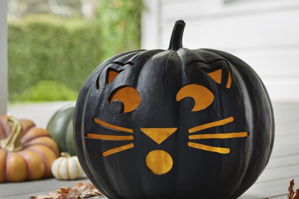 This photo provided by Balsam Hill shows a jack-o-lantern with a feline face. Black cats, celestial imagery and ravens are decorative elements that have a cool Halloween vibe without being overly scary. (Balsam Hill via AP)