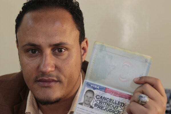 Mohammed Al Zabidi holds his canceled U.S. visa at his home in Sanaa, Yemen, on Thursday, Jan. 28, 2021. The Trump administration’s travel ban that affected several Muslim-majority nations robbed him of his American dream and his chance to escape his war-torn homeland. With a new president at the helm, the ban is over, but Al Zabidi’s plight isn’t. (AP Photo/Hani Mohammed)