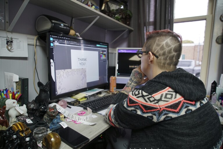 Melissa Sell uses her computer to work on inventory at her shop, Every Witch Way, in Mount Holly Springs, Pa., on Monday, Oct. 30, 2023. Sell said she believes the level of distrust is now so high that a civil war or some other kind of uprising could happen — but that it would be the government that starts it. (AP Photo/Allen G. Breed)