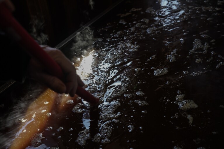 Bob Martin stirs maple syrup, Sunday, Feb. 25, 2024, in Rhinelander, Wis. In many parts of Wisconsin and the Midwest this year, the warmest winter on record drove farmers and hobbyists alike to start collecting tree sap for maple syrup a month or more earlier than they normally would. (AP Photo/Joshua A. Bickel)