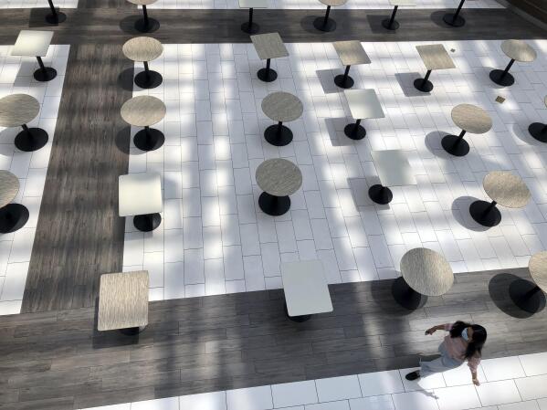 A woman wearing a protective mask walks through the mostly empty food court as Alabama's largest shopping mall, the Riverchase Galleria reopened in Hoover, Ala., Tuesday, May 5, 2020. Dozens of stores, including major retailers, remained closed as the mall opened for business for the first time during the coronavirus pandemic. (AP Photo/Jay Reeves)