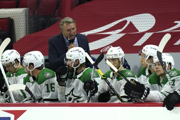 Dallas Stars coach Rick Bowness, top, speaks with his players during the second period of an NHL hockey game against the Carolina Hurricanes in Raleigh, N.C., Saturday, April 3, 2021. (AP Photo/Gerry Broome)