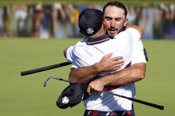 United States' Brian Harman, left, embraces United States' Max Homa on the 16th green as they win their morning Foursomes match 4&2 at the Ryder Cup golf tournament at the Marco Simone Golf Club in Guidonia Montecelio, Italy, Saturday, Sept. 30, 2023. (AP Photo/Gregorio Borgia )