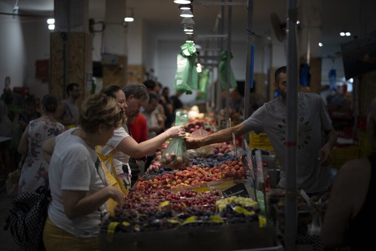 A woman buys fruit in a local market in Haifa, Israel, on Aug. 16, 2024. (AP Photo/Leo Correa)