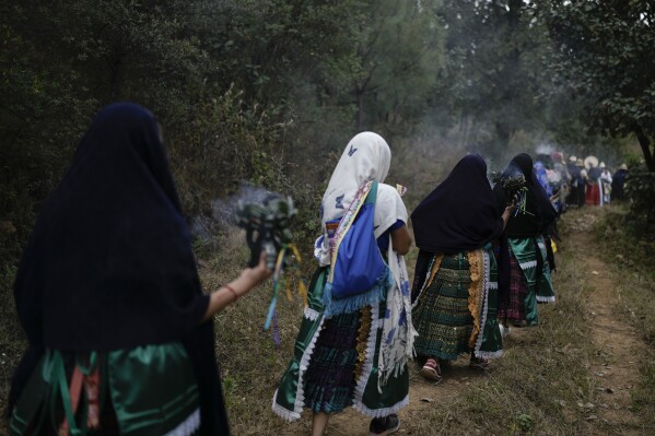 Purepecha Indigenous women carry burning copal incense as they escort a flame from Erongaricuaro, where residents kept the fire alive for one year, to Ocumicho in Michoacan state, Mexico, Wednesday, Jan. 31, 2024. To mark the new year, based on an ancient lunar calendar, a new flame will be lit during a “New Fire” ceremony on Feb. 2. (AP Photo/Eduardo Verdugo)
