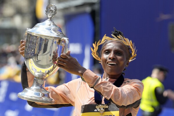 Hellen Obiri, of Kenya, displays the trophy on finish line after winning the women's division at the Boston Marathon, Monday, April 15, 2024, in Boston. (AP Photo/Steven Senne)
