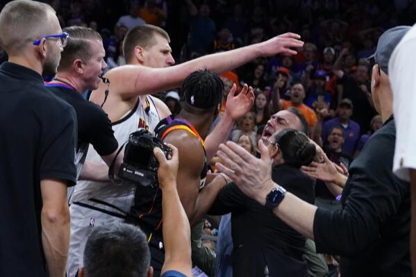 Denver Nuggets center Nikola Jokic get into an altercation in the stands during the first half of Game 4 of an NBA basketball Western Conference semifinal game against the Phoenix Suns, Sunday, May 7, 2023, in Phoenix. (AP Photo/Matt York)