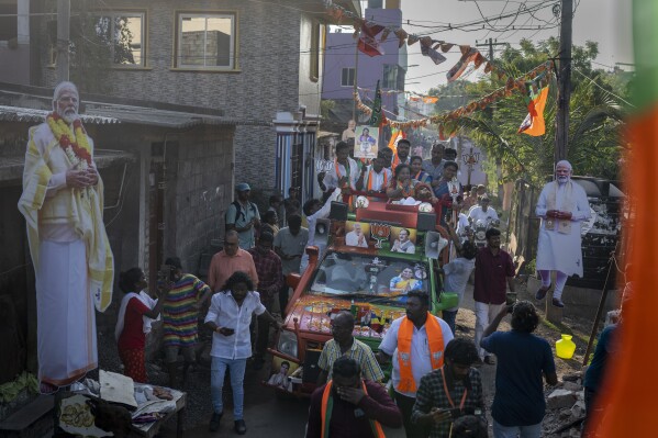 Large cutout portraits of Indian Prime Minister Narendra Modi are displayed along the route as Bharatiya Janata Party (BJP) candidate Tamilisai Soundararajan rides on top of a vehicle during a roadshow ahead of country's general elections, in the southern Indian city of Chennai, April 14, 2024. (AP Photo/Altaf Qadri)