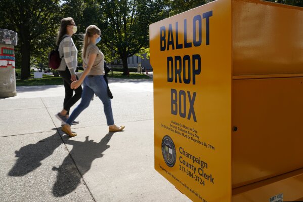 FILE - In this Oct. 6, 2020, file photo, University of Illinois students walk past a mail-in ballot drop box that sits on the northwest corner of the university's Quad in Urbana, Ill. As it has for more than 170 years, The Associated Press will count the vote and report the results of presidential, congressional and state elections quickly, accurately and without fear or favor on Nov. 3 and beyond. (AP Photo/Charles Rex Arbogast, File)