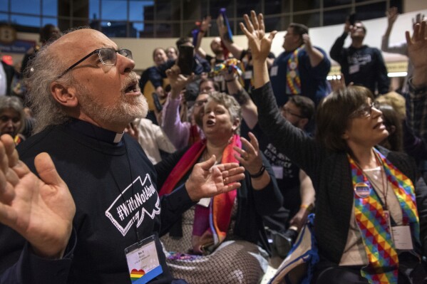 FILE - The Rev. K Karen, left, of St. Paul & St. Andrew United Methodist Church in New York joins other protesters in song and prayer outside the United Methodist Church's special session of the general conference in St. Louis, Tuesday, Feb. 26, 2019. Since 2019, the denomination has lost about one-fourth of its U.S. churches in breakup focused in large part on whether to accept same-sex marriage and ordination of LGBT clergy. (AP Photo/Sid Hastings, File)
