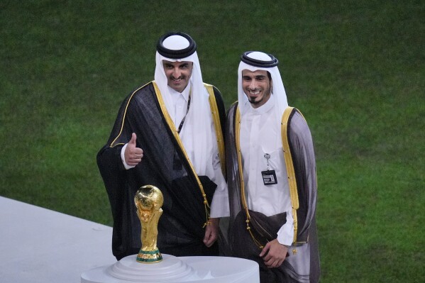 FILE - Emir of Qatar Tamim bin Hamad Al Thani, left, gives thumbs up as he stands with his older brother Sheikh Jassim bin Hamad Al Thani on the podium after the World Cup final soccer match between Argentina and France at the Lusail Stadium in Lusail, Qatar, Sunday, Dec. 18, 2022. Qatar's Sheikh Jassim bin Hamad Al Thani is withdrawing his offer to buy Manchester United, a person with knowledge of the process told The Associated Press. (AP Photo/Hassan Ammar, File)