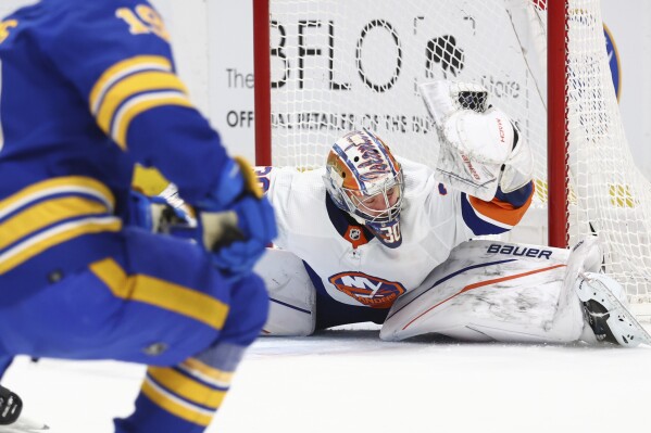 New York Islanders goaltender Ilya Sorokin, right, sprawls to make a glove-save on a shot by Buffalo Sabres center Peyton Krebs (19) during the first period of an NHL hockey game Thursday, March 14, 2024, in Buffalo, N.Y. (AP Photo/Jeffrey T. Barnes)