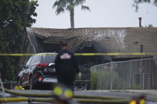Authorities work the scene where a small plane crashed into a San Diego neighborhood, setting several homes on fire and forcing evacuations along several blocks early Thursday, May 22, 2025. (AP Photo/Gregory Bull)