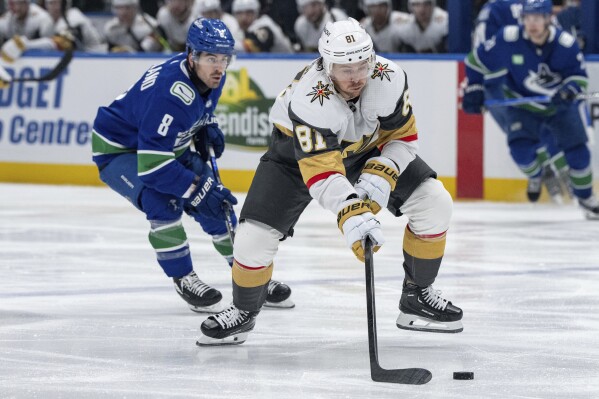 Vancouver Canucks' Conor Garland (8) and Vegas Golden Knights' Jonathan Marchessault (81) vie for the puck during the third period of an NHL hockey game in Vancouver, British Columbia, on Monday, April 8, 2024. (Ethan Cairns/The Canadian Press via AP)