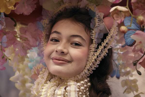 A reveler wearing decorated hat and costume pause for a portrait as she participates in the annual Easter Parade and Bonnet Festival in front of St. Patrick's Cathedral on Sunday, April 20, 2025, in New York. (AP Photo/Andres Kudacki)