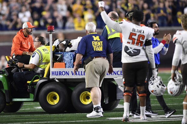 Bowling Green linebacker Demetrius Hardamon is carted away with an injury as offensive tackle Armon Bethea (56) raises his arm in support during the second half of an NCAA college football game against Michigan, Saturday, Sept. 16, 2023, in Ann Arbor, Mich. (AP Photo/Jose Juarez)