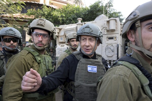FILE - Israeli Prime Minister Benjamin Netanyahu, center, wears a protective vest and helmet as he receives a security briefing with commanders and soldiers in the northern Gaza Strip, on Monday, Dec. 25, 2023. Netanyahu has said Israel will continue with the offensive until a "final victory" achieves all of its goals. He expects the war to last throughout 2024 and has resisted calls from the U.S. and other allies to lay out a clear postwar plan for Gaza. (Avi Ohayon/GPO/Handout via AP, File)