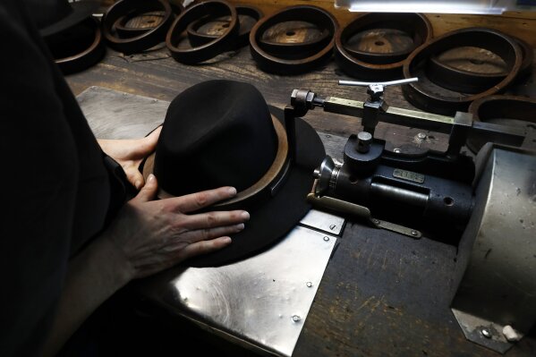 
              A man holds a hat inside the Borsalino hat factory, in Spinetta Marengo, near Alessandria, Italy, Thursday, Jan. 17, 2019. Borsalino's prized felt hats are handmade by 80 workers in its Piemonte factory, many who have worked there for decades, with original machinery that use hot water and steam to transform rabbit fur into highly prized felt, that is formed into clochards, dyed and molded by hand to create the latest styles.  (AP Photo/Antonio Calanni)
            