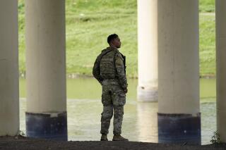 FILE - A member of the Texas National Guard looks across the Rio Grande to Mexico from the U.S. at Eagle Pass, Texas, on Aug. 26, 2022. At least eight migrants were killed as dozens attempted a hazardous crossing of the Rio Grande near Eagle Pass, Texas, officials said Friday, Sept. 2, 2022. U.S. Customs and Border Protection reported that it responded to the report a day earlier. (AP Photo/Eric Gay, File)