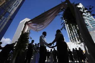 FILE - A couple holds hands as they are married by a county clerk during a Valentine's Day group wedding ceremony on the steps of the Dade County Courthouse in Miami, Wednesday, Feb. 14, 2024. U.S. marriages have rebounded to pre-pandemic levels with nearly 2.1 million in 2022, a 4% increase from the year before, the Centers for Disease Control and Prevention said in a report published Friday, March 15, 2024. (AP Photo/Rebecca Blackwell, File)