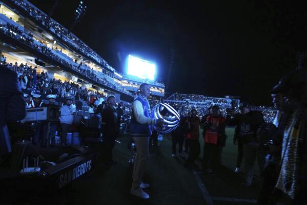 San Diego FC founding partner Manny Machado carries an illuminated ball during a ceremony before the team hosts an MLS soccer match against St. Louis City Saturday, March 1, 2025, in San Diego. (AP Photo/Gregory Bull)