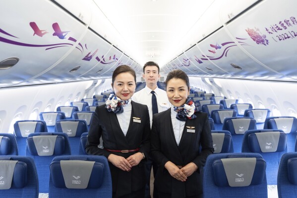 Members of the aircraft crew pose for photographs inside the Chinese-made C919 at the Hong Kong International Airport in Hong Kong, on Wednesday, Dec. 13, 2023. Chinese aerospace company COMAC has showcased its domestically-developed C919 passenger jet in Hong Kong, giving officials and media a close-up look at the narrow-bodied aircraft. A welcome ceremony for the C919 and another Chinese-made jet, the ARJ21, was held at the Hong Kong international airport on Wednesday, a day after both flew into Hong Kong for the first time. (AP Photo/Chan Long Hei)