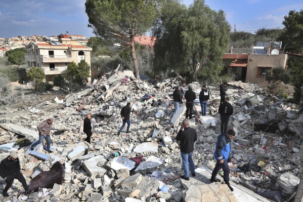 Lebanese citizens gather on the grounds of a house destroyed by an Israeli airstrike Tuesday evening, in Bint Jbeil, South Lebanon, Wednesday, December 27, 2023. A Hezbollah fighter and two civilians, a newlywed couple, were killed during the night.  Israeli strike on a family residential building in the town of Bint Jbeil, local residents and state media said on Wednesday.  (AP Photo/Mohammed Zaatari)