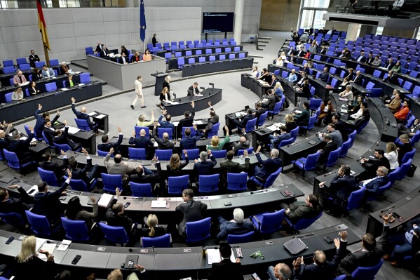 MPs vote during the 164th session of the Bundestag, the parliament's lower house, in Berlin, Germany, Friday April 12, 2024. The German parliament on Friday approved legislation introducing payment cards for asylum-seekers, a system that is meant to limit benefits paid in cash and make the country less attractive for migrants. (Britta Pedersen/dpa via AP)