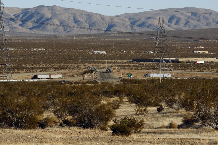 FILE - This photo Jan. 25, 2012, photo shows the site of a proposed station for a high-speed rail line to Las Vegas, foreground, with Interstate 15 in the background, on the far outskirts of Victorville, Calif., the Mojave Desert city on the route from Los Angeles to Las Vegas. Brightline West and U.S. transportation secretary and other officials projecting that millions of ticket-buyers will be boarding trains by 2028. (AP Photo/Reed Saxon)