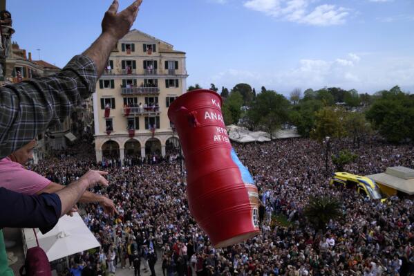 People throw a huge clay jar from a balcony as thousands of visitors watch the custom called "botides" on the Ionian Sea island of Corfu, northwestern Greece, on Saturday, April 23, 2022. For the first time in three years, Greeks were able to celebrate Easter without the restrictions made necessary by the coronavirus pandemic. (AP Photo/Thanassis Stavrakis)