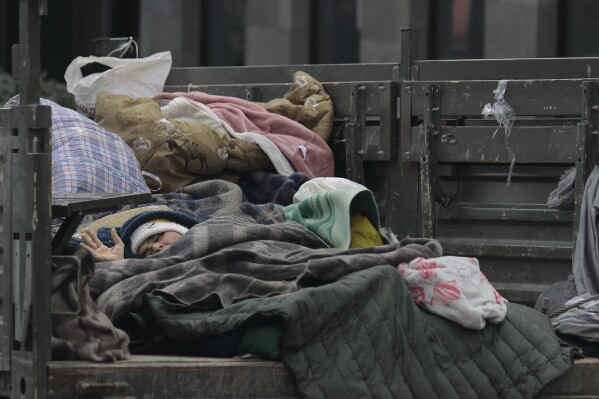 An ethnic Armenian woman fleeing Nagorno-Karabakh lies in the bed of a truck as she arrives in Goris, in Armenia's Syunik region, Wednesday, Sept. 27, 2023. (AP Photo/Vasily Krestyaninov)