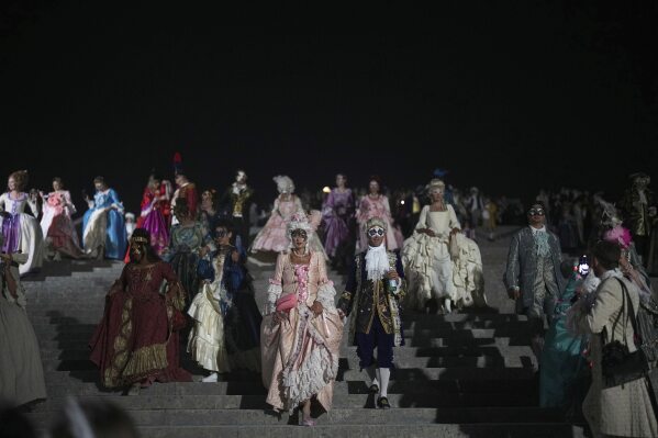 Costumed guests arrive for the Great Masked Ball in the Orangerie of the Versailles castle, outside Paris, Saturday, June 21, 2025. (AP Photo/Christophe Ena)