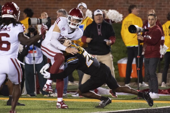 Oklahoma quarterback Jackson Arnold (11) is hit by Missouri cornerback Nicholas Deloach Jr., right, before he scores a touchdown during the second half of an NCAA college football game Saturday, Nov. 9, 2024, in Columbia, Mo. Missouri won 30-23. (AP Photo/L.G. Patterson)