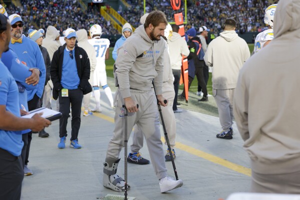 Los Angeles Chargers linebacker Joey Bosa walks with a boot and crutches on the sideline during the second half of an NFL football game against the Green Bay Packers, Sunday, Nov. 19, 2023, in Green Bay, Wis. (AP Photo/Matt Ludtke)