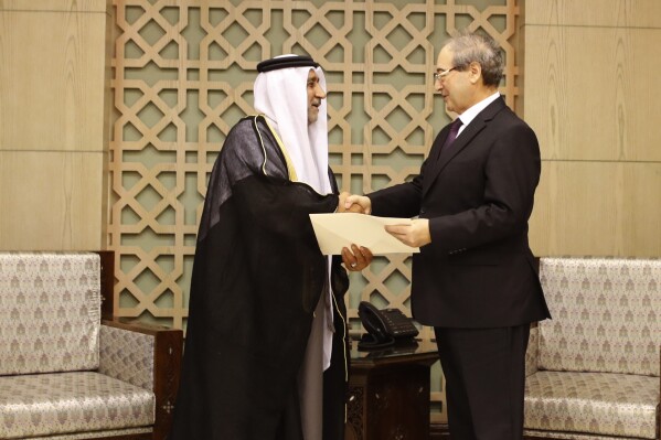 Syrian Foreign Minister Faisal Mekdad, right, shakes hands with the new United Arab Emirates Ambassador to Syria Hassan Ahmad al-Shihi and receive his credentials, in Damascus, Syria, Tuesday, January. 30, 2024. The first United Arab Emirates ambassador to Damascus in nearly 13 years took up his post on Tuesday as Syria has been reintegrating into mainstream regional acceptance. (AP Photo/Omar Sanadiki)
