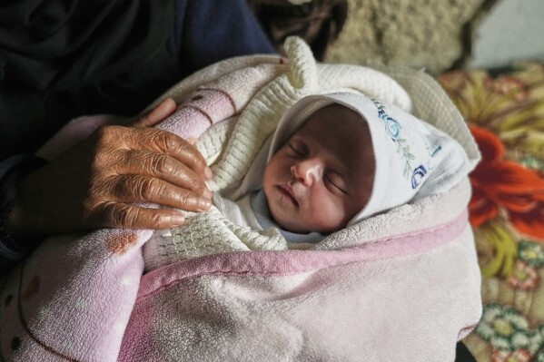 Ella Osama Abu Dagga, 25 days old, is held by her great-aunt Suad Abu Dagga, after she was pulled from the rubble earlier following an Israeli army airstrike that killed her parents and brother, in Khan Younis, southern Gaza Strip, Thursday, March 20, 2025. (AP Photo/Abdel Kareem Hana )