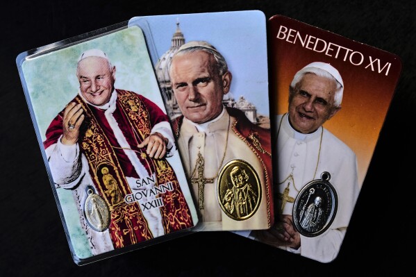 From left to right: religious memorabilia depicting Pope John XXIII, John Paul II and Pope Benedict XVI in Rome, Thursday, May 1, 2025. (AP Photo/Bernat Armangue)