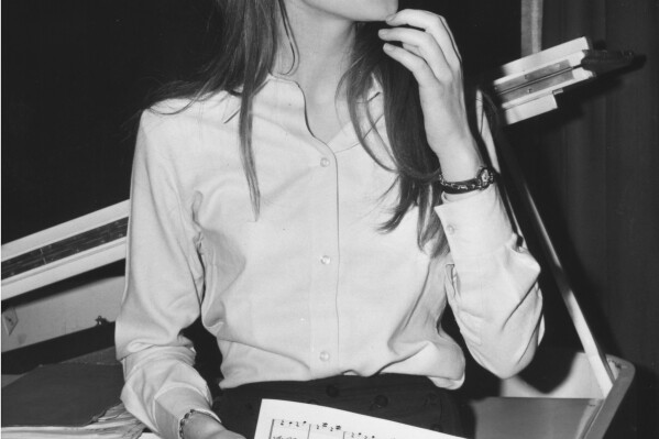 FILE - French singing star, Francoise Hardy, looks at a music score during a break in rehearsals, January 31, 1966, at the Savoy Hotel in London, England, where she is to appear for a three-week cabaret spot. Francoise Hardy, a beloved French singer and pop culture icon since the 1960s, has died at age 80. Her son, musician Thomas Dutronc, announced her death on social networks. (AP Photo, File)