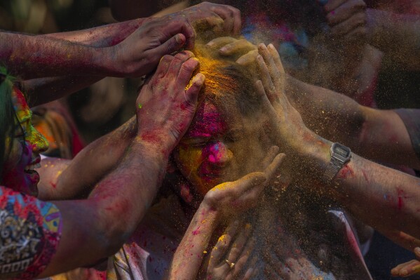 A girl has her face smeared with coloured powder as they celebrate Holi, the festival of colors in Mumbai, India, Monday, March 25, 2024. (AP Photo/Rafiq Maqbool)