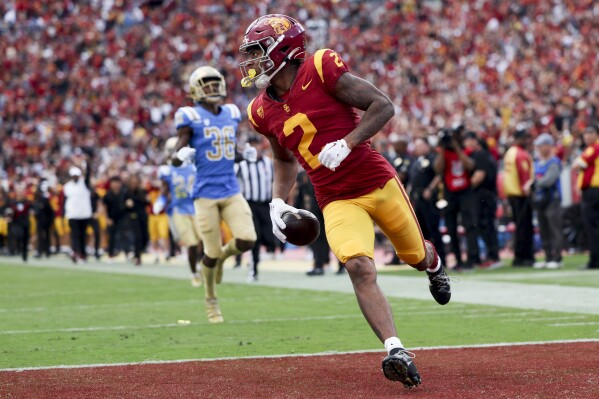 Southern California wide receiver Brenden Rice, right, runs in the end zone for a touchdown as UCLA defensive back Alex Johnson watches during the first half of an NCAA college football game, Saturday, Nov. 18, 2023, in Los Angeles. (AP Photo/Ryan Sun)